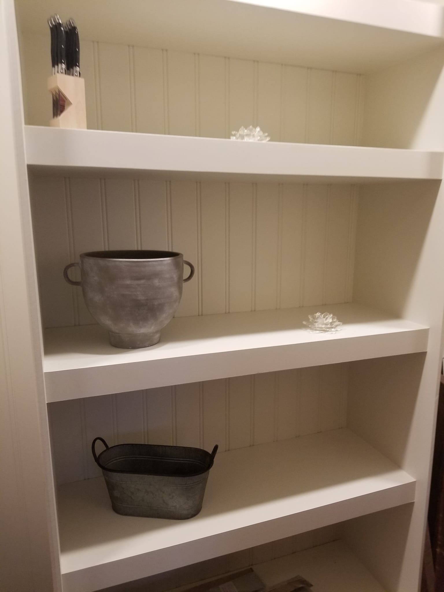 White painted shelving unit with beadboard backing